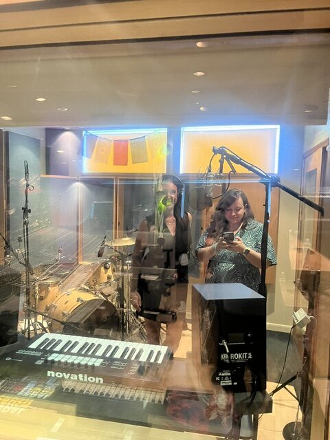 Two people in recording studio with keyboard, drums