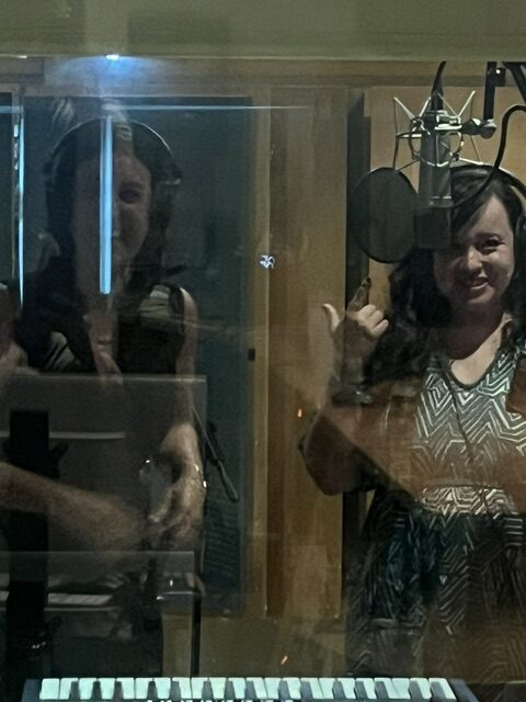 Two women recording in music studio with microphone